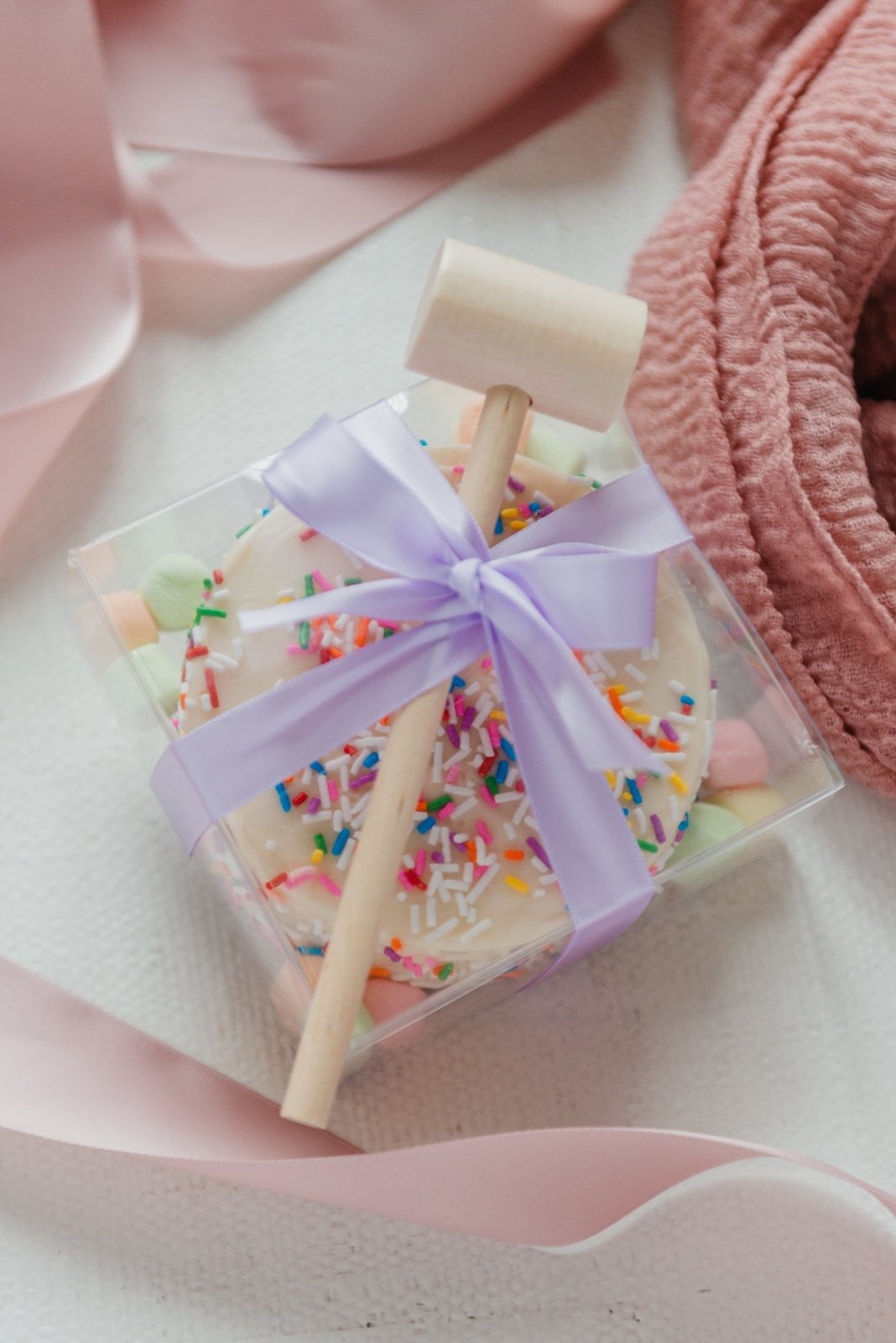 Small square candy with a purple bow on a pink background