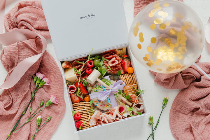 Gift box with food items, flowers, and a balloon on a white background