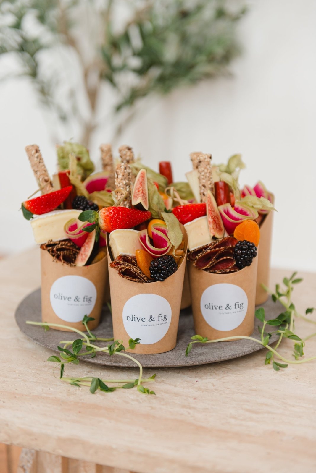 Assorted appetizers in paper cups on a wooden table with a blurred natural background