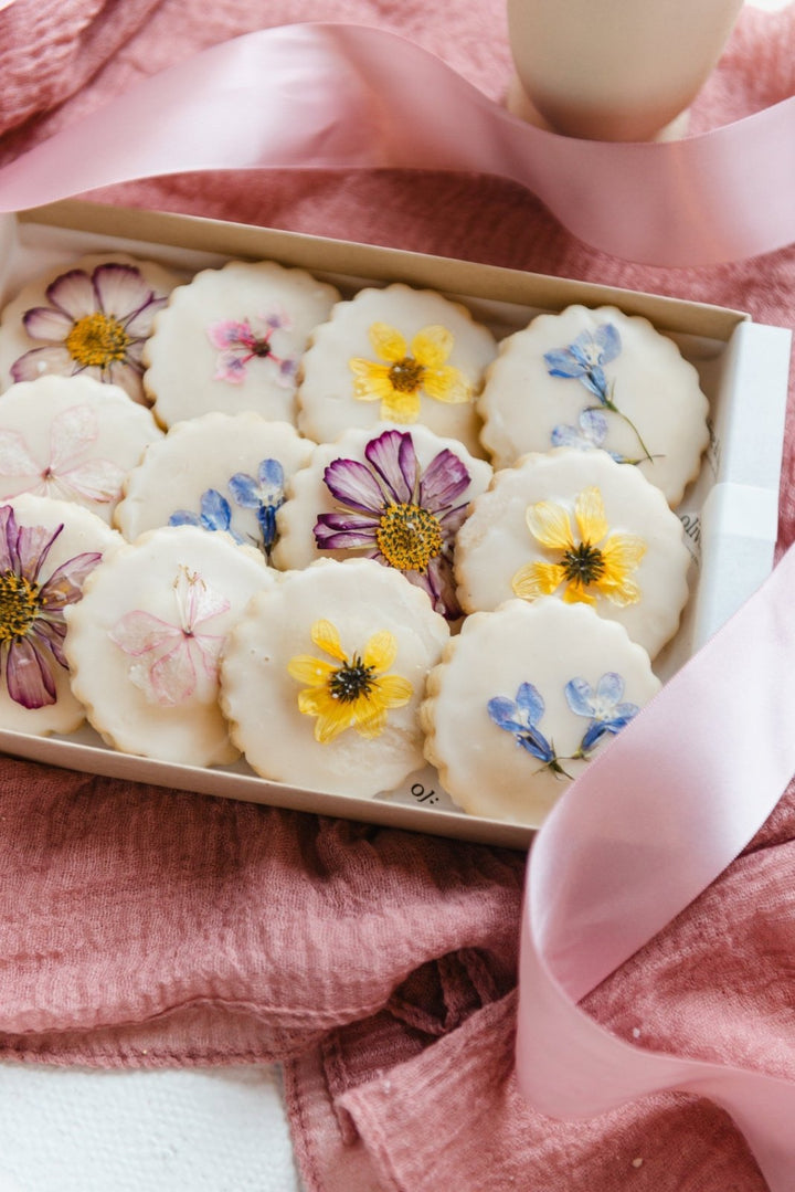 Box of cookies with floral decorations on a pink fabric background