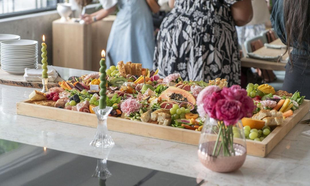 Gourmet platter with various foods on a table, people in the background