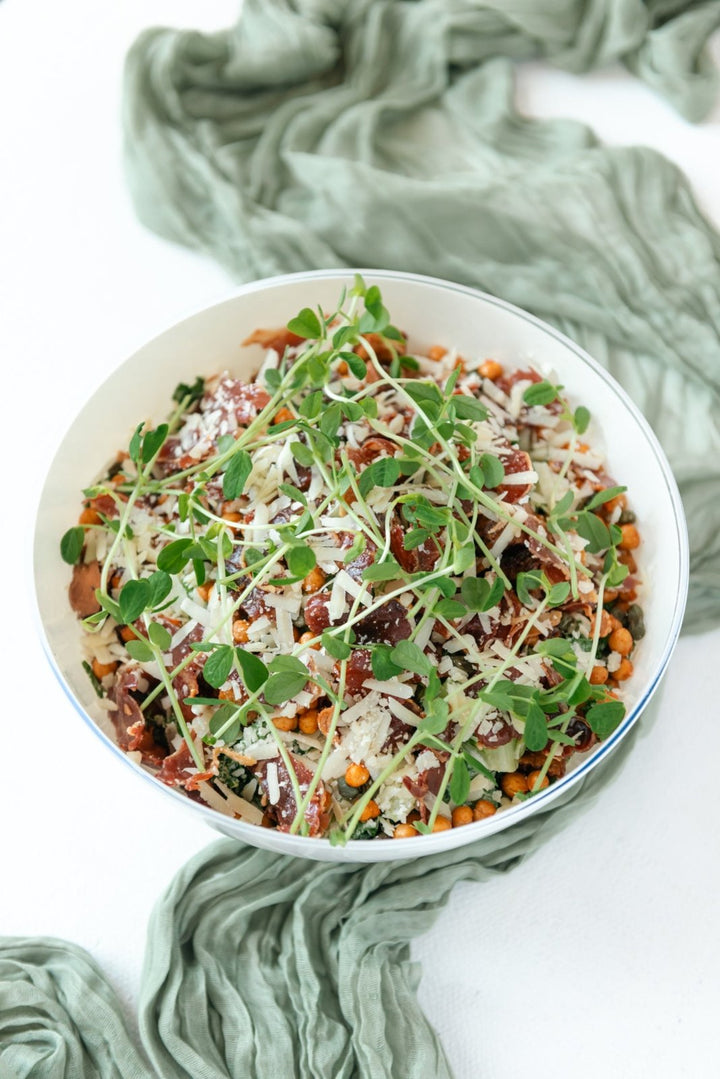 Salad with greens and other ingredients in a white bowl on a light background
