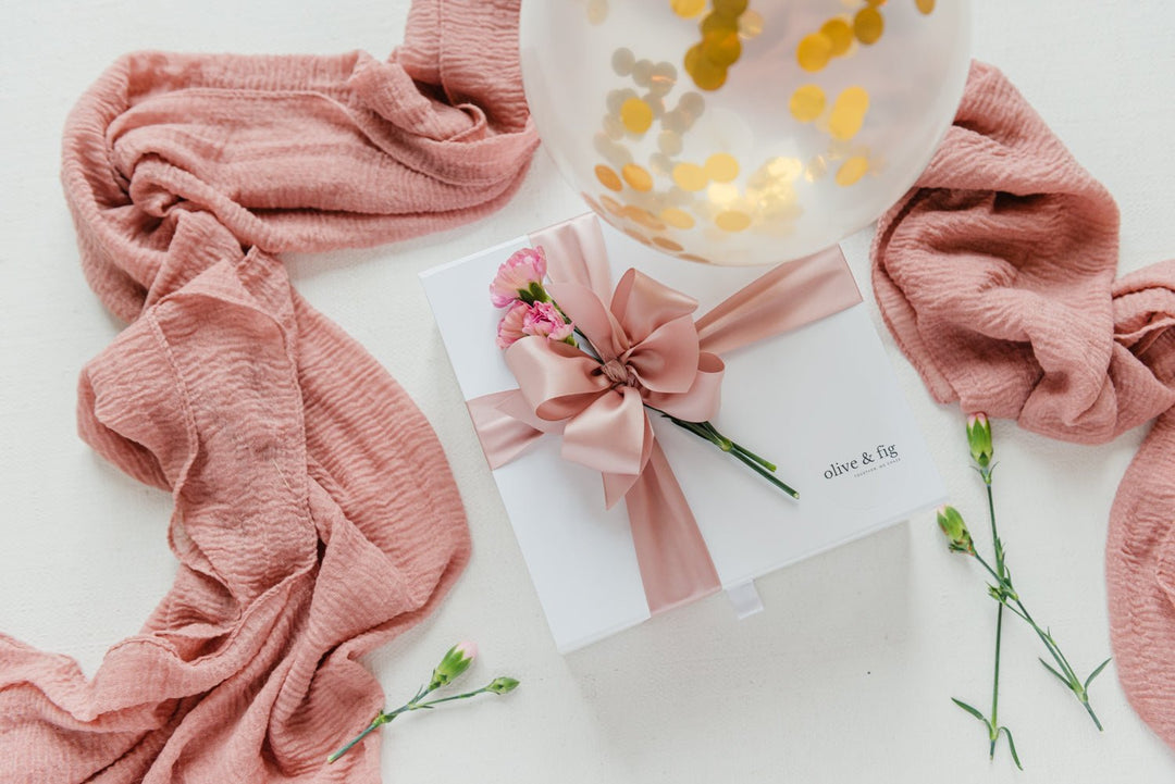 Pink textured fabric, gift card, and flowers on a white surface