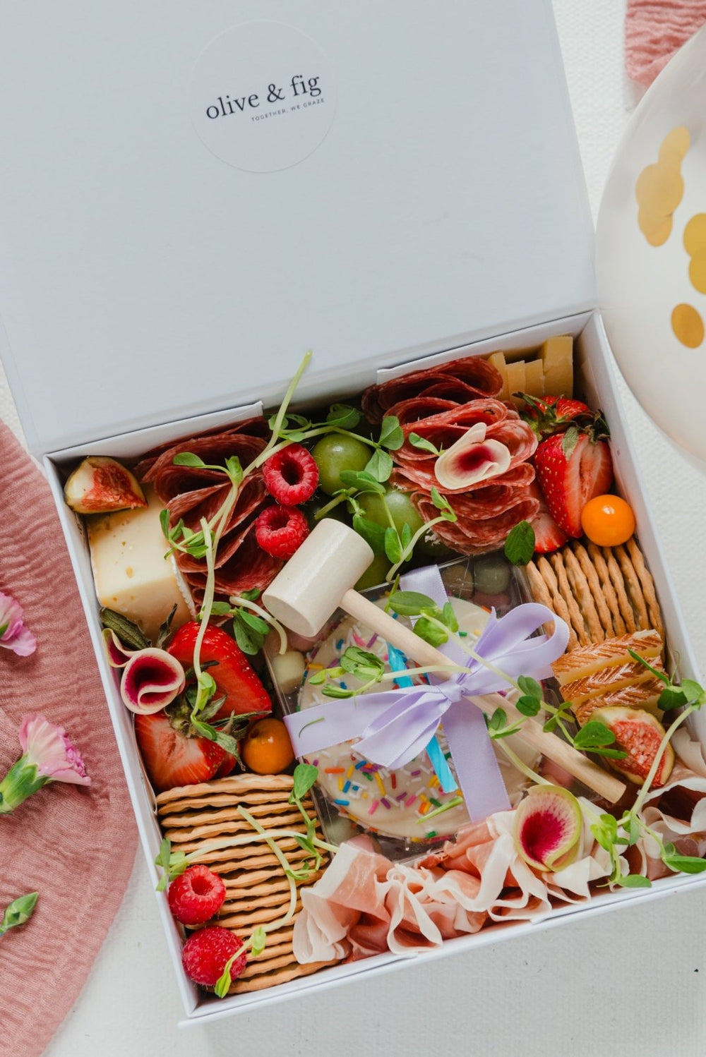 Open box of assorted meats, cheeses, and fruits with 'olive & fig' branding.