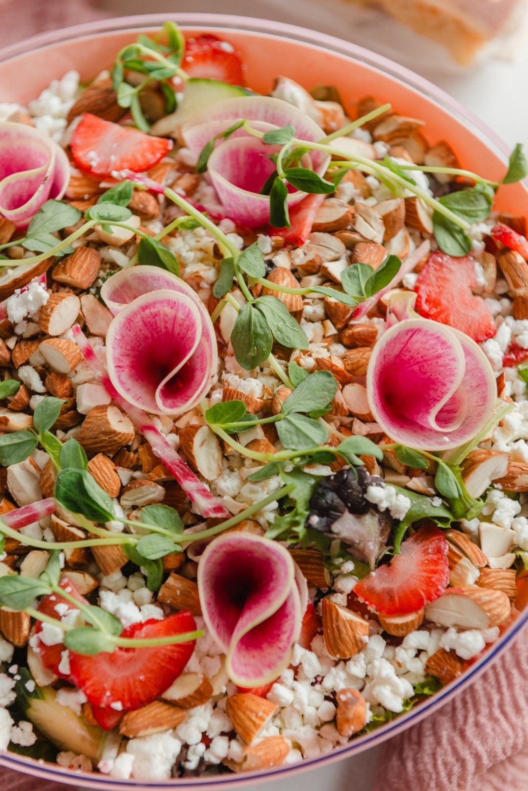 Colorful salad with strawberries, almonds, and greens in a bowl.