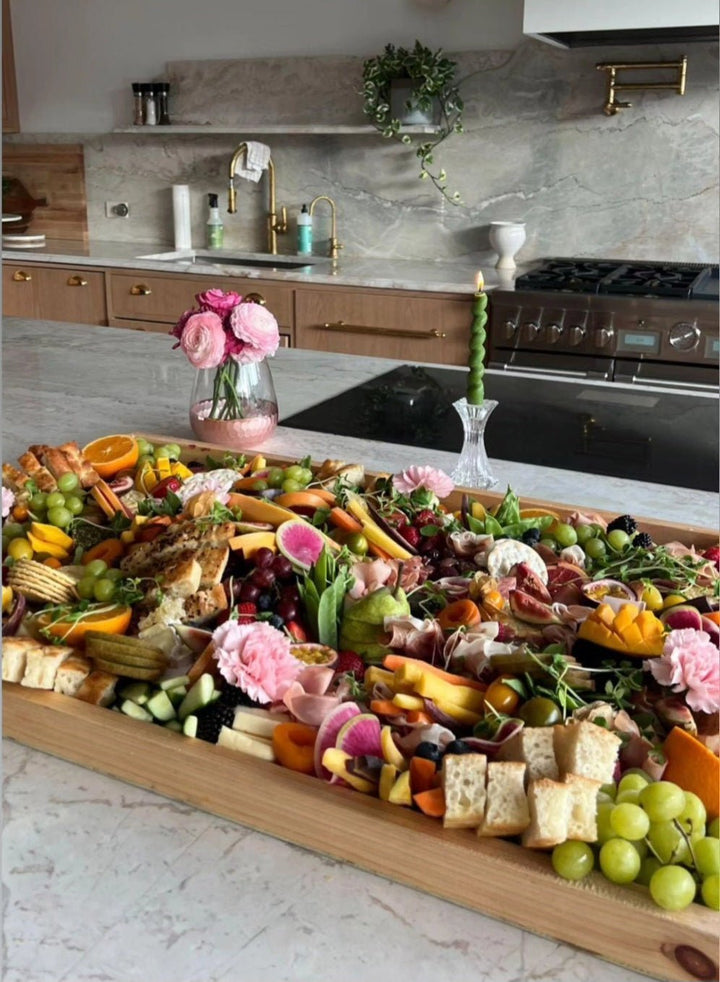 Gourmet charcuterie board with fruits, meats, and bread on a kitchen counter.