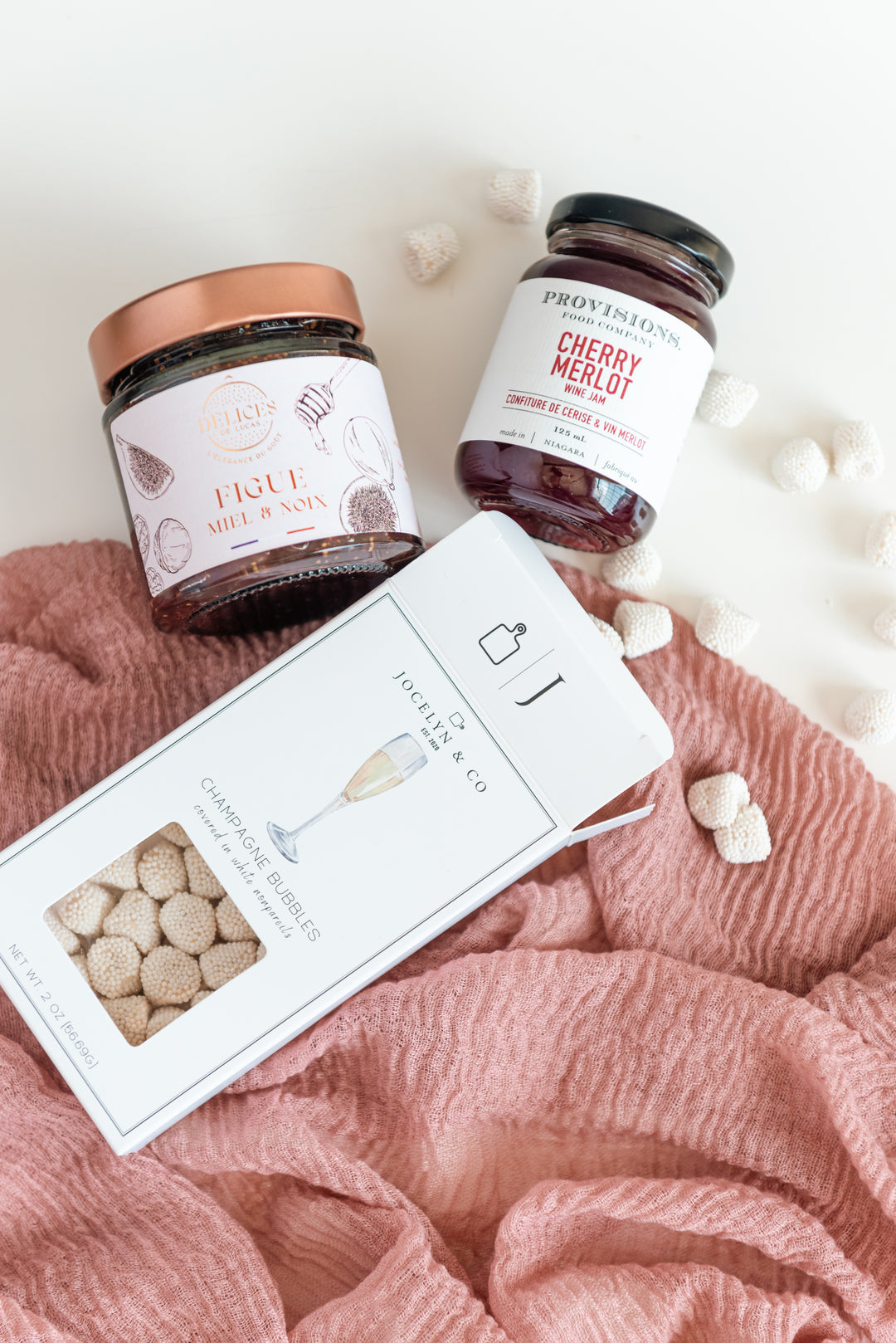 Two jars of jam and a box on a pink fabric background