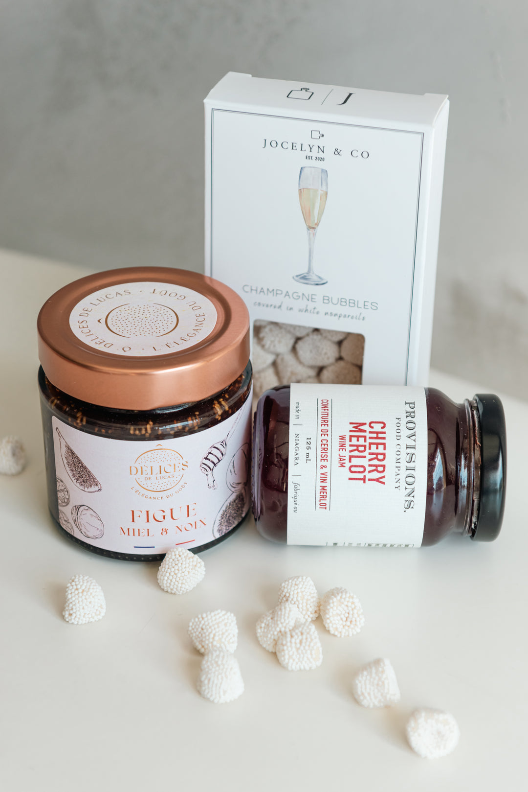 Jars of honey and a box labeled 'Jocelyn & Co' on a light surface with white spherical objects.